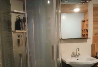 Moderne badkamer in Emperor Bell Tent, Campsite Junora te Frankrijk, met douche, lavabo en spiegel.
