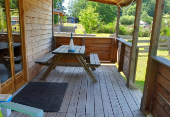 Terrasse en bois avec table de pique-nique au « Self-sufficient, luxury eco-chalet » du Camping Junora en France.
