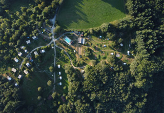 Vista aerea del campeggio Junora in Francia, con il lodge Avignon e tende tra alberi e prati verdi.