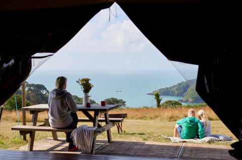 View from a tent at BoerenBed Fountain Violet Farm holiday park, showing people enjoying the sea and scenery.