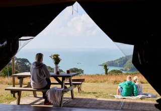 View from a tent at BoerenBed Fountain Violet Farm holiday park, showing people enjoying the sea and scenery.