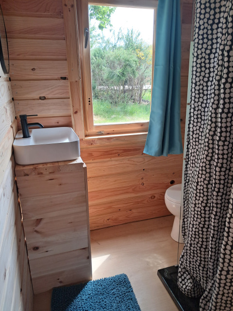 Kleine houten badkamer bij Avignon, Campsite Junora met raam, douche, toilet en blauwe mat.