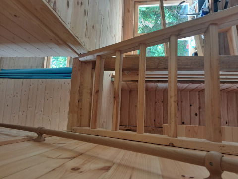 Interno in legno del lodge Avignon al campeggio Junora in Francia, con ringhiera e finestra.