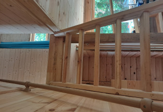 Houten interieur van lodge Avignon op Camping Junora in Frankrijk, met trapleuning en raam.