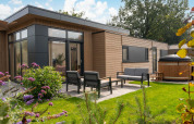 Outdoor view of the modern Cannenburch Deluxe lodge with patio and hot tub at Veluwe park de Bosgraaf, Netherlands.