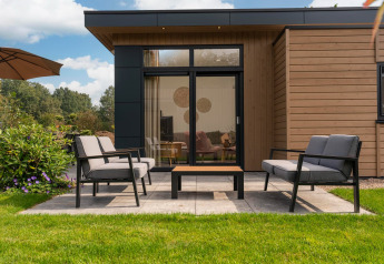 Modern Cannenburch Deluxe lodge with patio and outdoor furniture at Veluwe park de Bosgraaf, Netherlands.