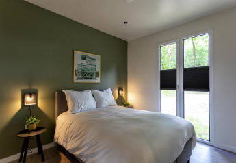 Moderne slaapkamer in Forest Cottage, Holiday Park BreeBronne, Nederland, met bed en groene muur.