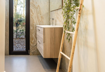 Modern bathroom in Forest Cottage featuring wood vanity, decorative ladder, and forest view at BreeBronne.