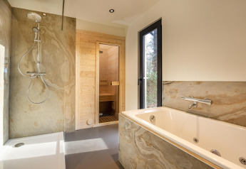 Salle de bain moderne avec douche, baignoire, sauna et fenêtre au Forest Cottage, Holiday Park BreeBronne.