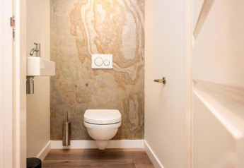 Moderne toilet med væghængt toilet, lille håndvask og marmorinspireret væg i Forest Cottage, BreeBronne.