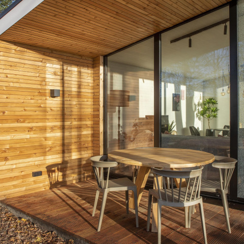 Terrasse en bois avec table ronde et quatre chaises au Forest Cottage, Holiday Park BreeBronne, Pays-Bas.