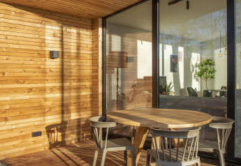 Wooden terrace with round table and four chairs at Forest Cottage, Holiday Park BreeBronne, Netherlands.