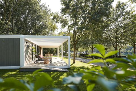 Terraza exterior en la lodge Forest Cube con tumbonas y mesa, rodeada de árboles verdes y césped.