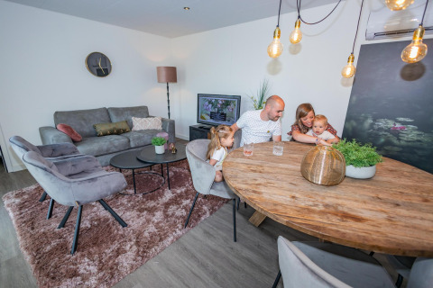 Familie verbringt Zeit zusammen in einer modernen Forest Cube Lodge im Holiday Park BreeBronne, Niederlande.