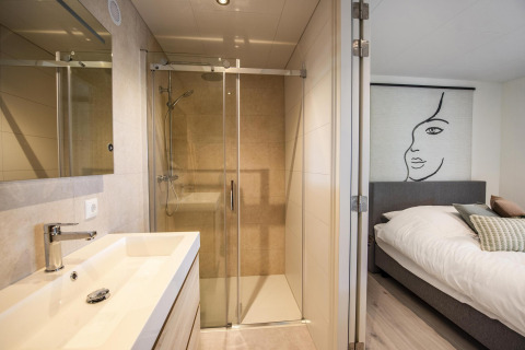 Lodge moderno en Forest Cube, BreeBronne, Países Bajos, con baño luminoso y dormitorio confortable.