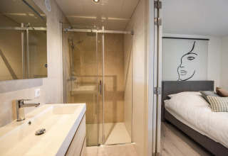 Moderne lodge på Forest Cube i BreeBronne, Holland, med badeværelse og soveværelse i lyst design.