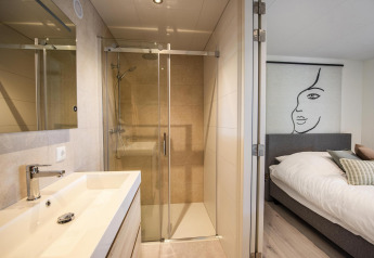 Modern lodge at Forest Cube, BreeBronne, Netherlands, showing bright bathroom and cozy bedroom areas.