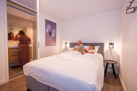 Familia relajándose en la habitación del Forest Cube en Holiday Park BreeBronne, Países Bajos.