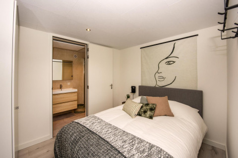 Chambre moderne à la Forest Cube lodge avec décoration murale artistique et vue sur la salle de bain.