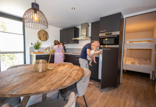 Gezin geniet samen in een moderne keuken in de Forest Cube lodge bij Holiday Park BreeBronne, Nederland.