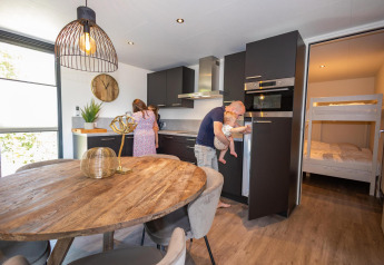 Family enjoys time together in a modern kitchen at Forest Cube lodge, Holiday Park BreeBronne, Netherlands.