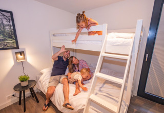 Gezin geniet samen op stapelbed in Forest Cube lodge, Holiday Park BreeBronne, Nederland.