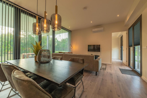 Moderne woon- en eetkamer in Forest Lodge van Holiday Park BreeBronne, Nederland, met zicht op natuur.