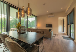 Moderne woon- en eetkamer in Forest Lodge van Holiday Park BreeBronne, Nederland, met zicht op natuur.