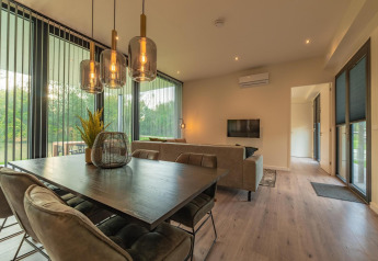 Modernes Wohn- und Esszimmer in der Forest Lodge im Holiday Park BreeBronne, mit großen Fenstern zur Natur.
