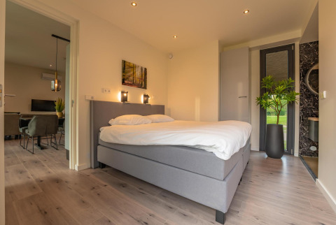Modern slaapkamer in Forest Lodge, Holiday Park BreeBronne, Nederland, met comfortabel bed en planten.