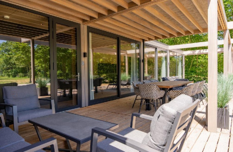 Terraza exterior con muebles modernos en Forest Villa, Holiday Park BreeBronne, Países Bajos, rodeada de naturaleza.