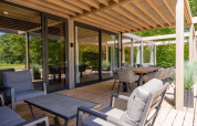 Terrasse extérieure avec mobilier moderne à Forest Villa, Holiday Park BreeBronne, Pays-Bas, entourée de verdure.