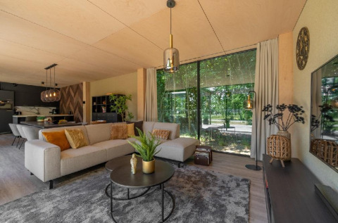 Salón moderno en Forest Villa de Holiday Park BreeBronne, Países Bajos, con grandes ventanales y vista al bosque.