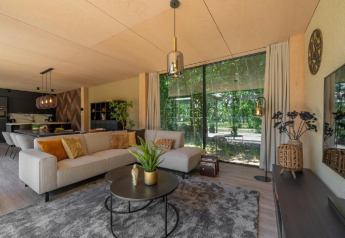 Salon moderne à la Forest Villa du Holiday Park BreeBronne, Pays-Bas, grandes baies et vue sur la forêt.