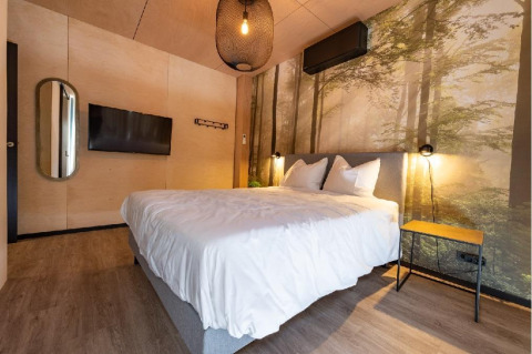 Dormitorio en Forest Villa de Holiday Park BreeBronne, Países Bajos, con decoración moderna y mural de bosque.