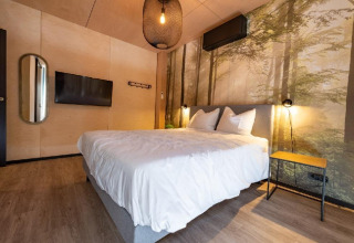 Dormitorio en Forest Villa de Holiday Park BreeBronne, Países Bajos, con decoración moderna y mural de bosque.