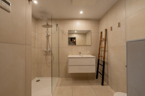 Baño moderno con ducha, espejo y lavabo en Forest Villa del Holiday Park BreeBronne, Países Bajos.