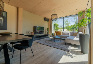 Modernes Wohnzimmer in der Forest Villa Lodge mit großen Fenstern, Sofa und Blick ins Grüne im BreeBronne Park.