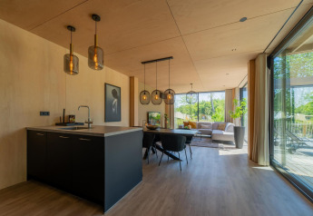 Moderne Forest Villa Lodge im Holiday Park BreeBronne, Niederlande, mit hellem Wohnbereich und großen Fenstern.