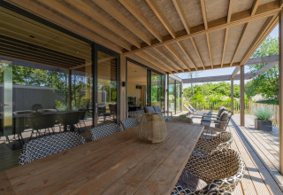 Terraza exterior de la Forest Villa en Holiday Park BreeBronne, Países Bajos, con muebles modernos de madera.