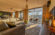 Salon moderne de la Forest Villa au Holiday Park BreeBronne, Pays-Bas, grandes fenêtres et décoration chaleureuse.
