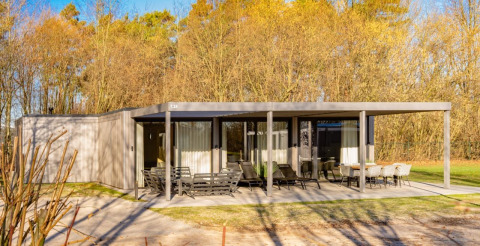 Buitenfoto van Forest Villa-lodge met moderne overdekte terras en tuinmeubels, omringd door bomen.