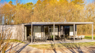 Photo extérieure du lodge Forest Villa avec terrasse moderne et mobilier de jardin entourés d’arbres.