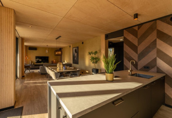 Interior moderno de lodge en Forest Villa, BreeBronne, Países Bajos, con isla de cocina y zona de estar.
