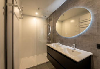 Moderne badkamer met dubbele lavabo, grote spiegel en douche in Forest Villa, BreeBronne, Nederland.