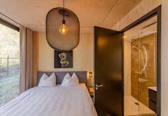 Chambre avec lit double, grande fenêtre et salle de bain à la Forest Villa, Holiday Park BreeBronne, Pays-Bas.