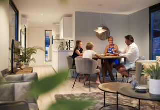 Gezin dineert samen aan tafel in een moderne lodge bij Water Cube, Holiday Park BreeBronne, Nederland.