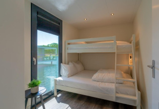 Moderne kamer in lodge "Water Cube" van Holiday Park BreeBronne, Nederland, met stapelbed en uitzicht op het water.