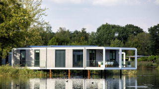 Moderna lodge Water Cube su un lago calmo, immersa nella natura rigogliosa, riflessa nell’acqua.