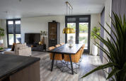 Zona giorno e pranzo moderna nella lodge Water Cube presso Holiday Park BreeBronne, Paesi Bassi, vista sul lago.